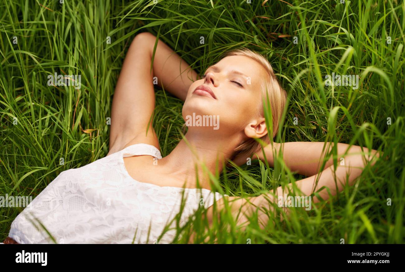 Schläft auf offenem Feld. Eine attraktive junge Frau, die auf einem grünen Feld schläft. Stockfoto