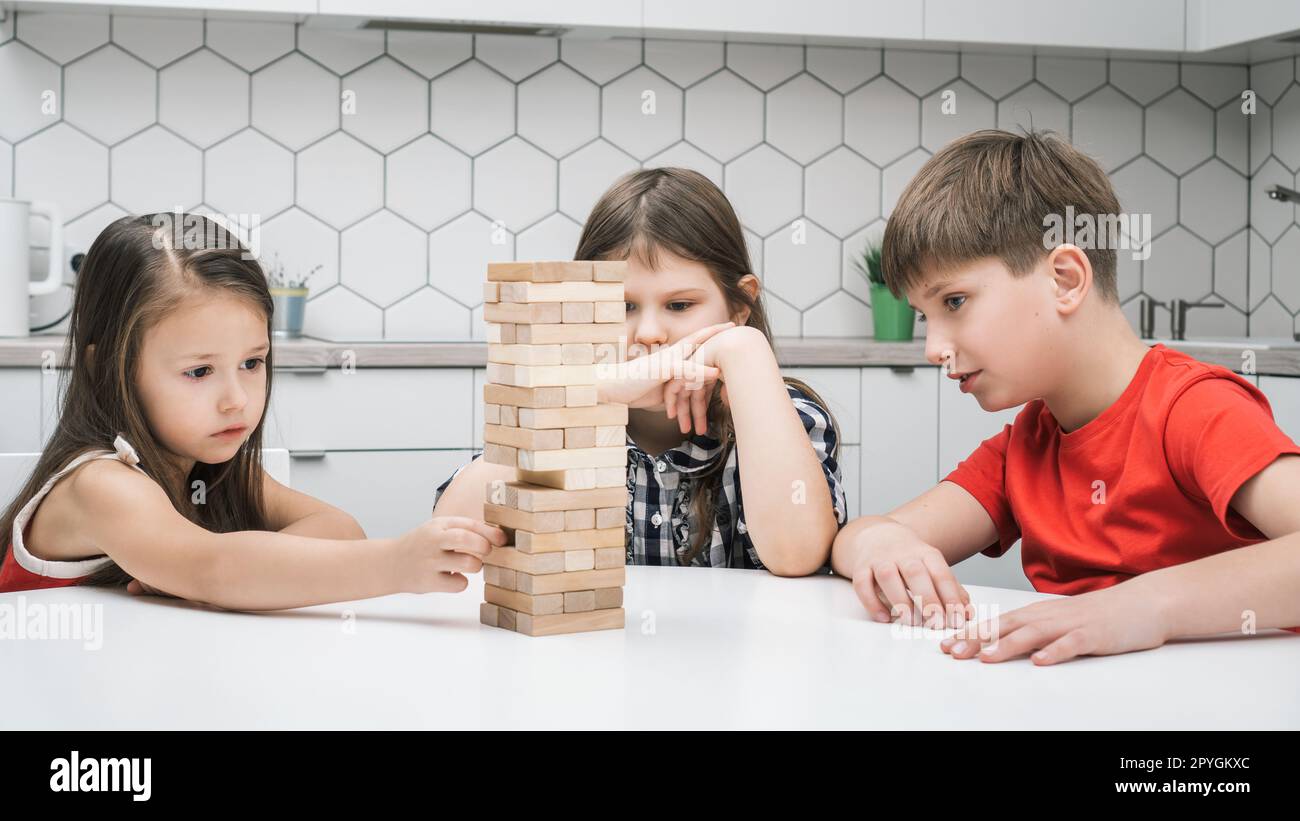 Gedanklich konzentrierte Kinder spielen das Balancieren des Spiels aus Ziegelsteinen und bauen Pyramiden auf dem Tisch. Ökologisches Bildungsspiel Stockfoto