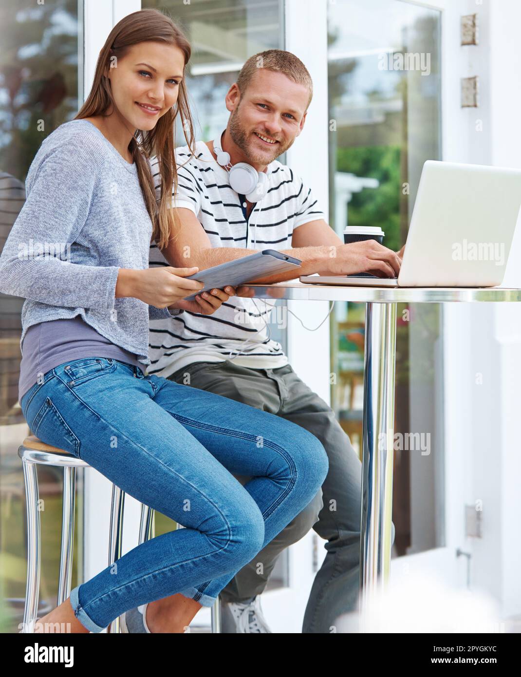 Partner im Leben und bei der Arbeit. Porträt eines glücklichen jungen Paares, das zusammen vor einem Café arbeitet. Stockfoto