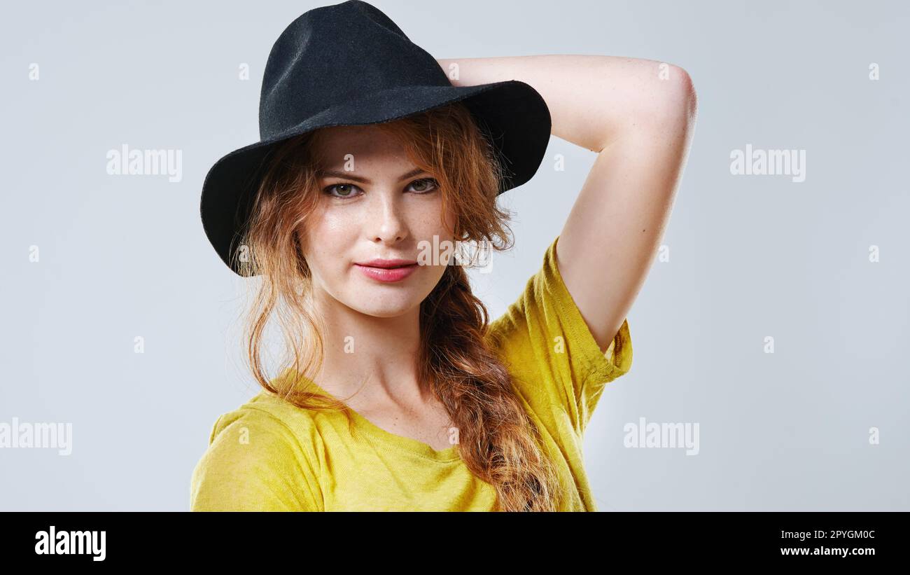 Stilvoll und fabelhaft. Verkürztes Studioporträt einer schönen jungen Frau mit schwarzem Hut. Stockfoto