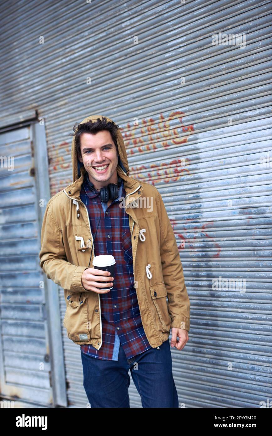 Das Leben ist kurz, genießen Sie Ihren Kaffee. Ein gutaussehender junger Mann steht draußen in der Kälte und trinkt eine warme Tasse Kaffee. Stockfoto