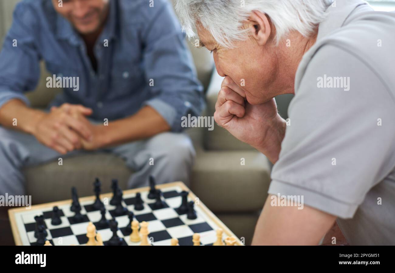 Er grübelte über seinen Zug. Ein Vater und Sohn, die zu Hause gemeinsam Schach spielen. Stockfoto
