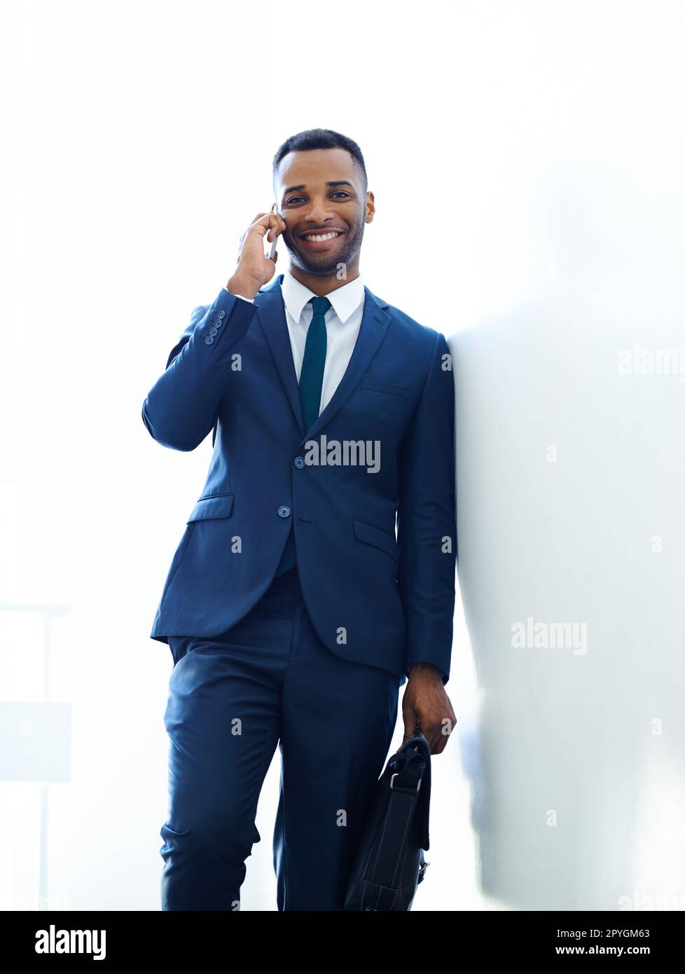 Treffen wir uns geschäftlich. Ein gutaussehender afroamerikanischer Geschäftsmann, der sein Smartphone in Innenräumen benutzt. Stockfoto