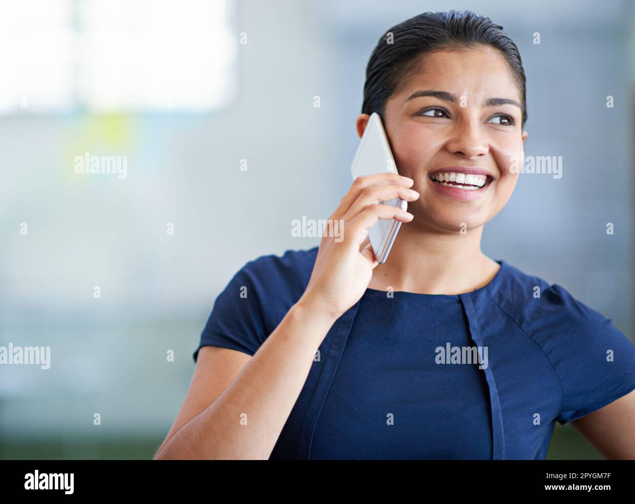 Schön, von Ihnen zu hören. Eine attraktive junge Geschäftsfrau, die ihr Handy im Büro benutzt. Stockfoto