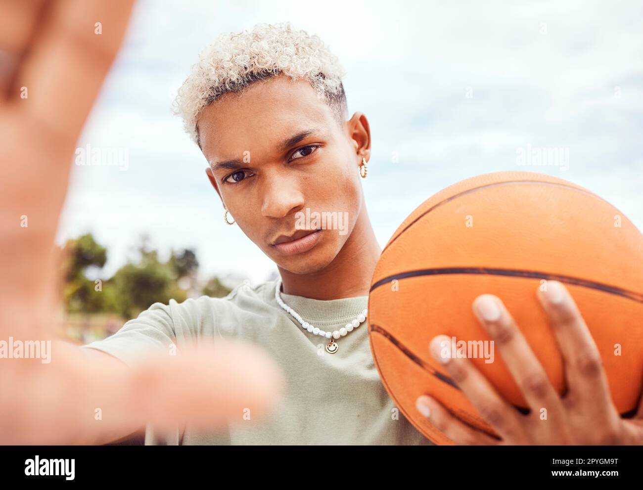 Sport-, Selfie- und Basketballspieler mit Mode und einem Ball, der auf einem Freiluftplatz steht. Fitness, trendiges und cooles Männermodell und Athlet aus Brasilien, der mit einem lässigen Outfit in der Stadt für ein Foto posiert Stockfoto