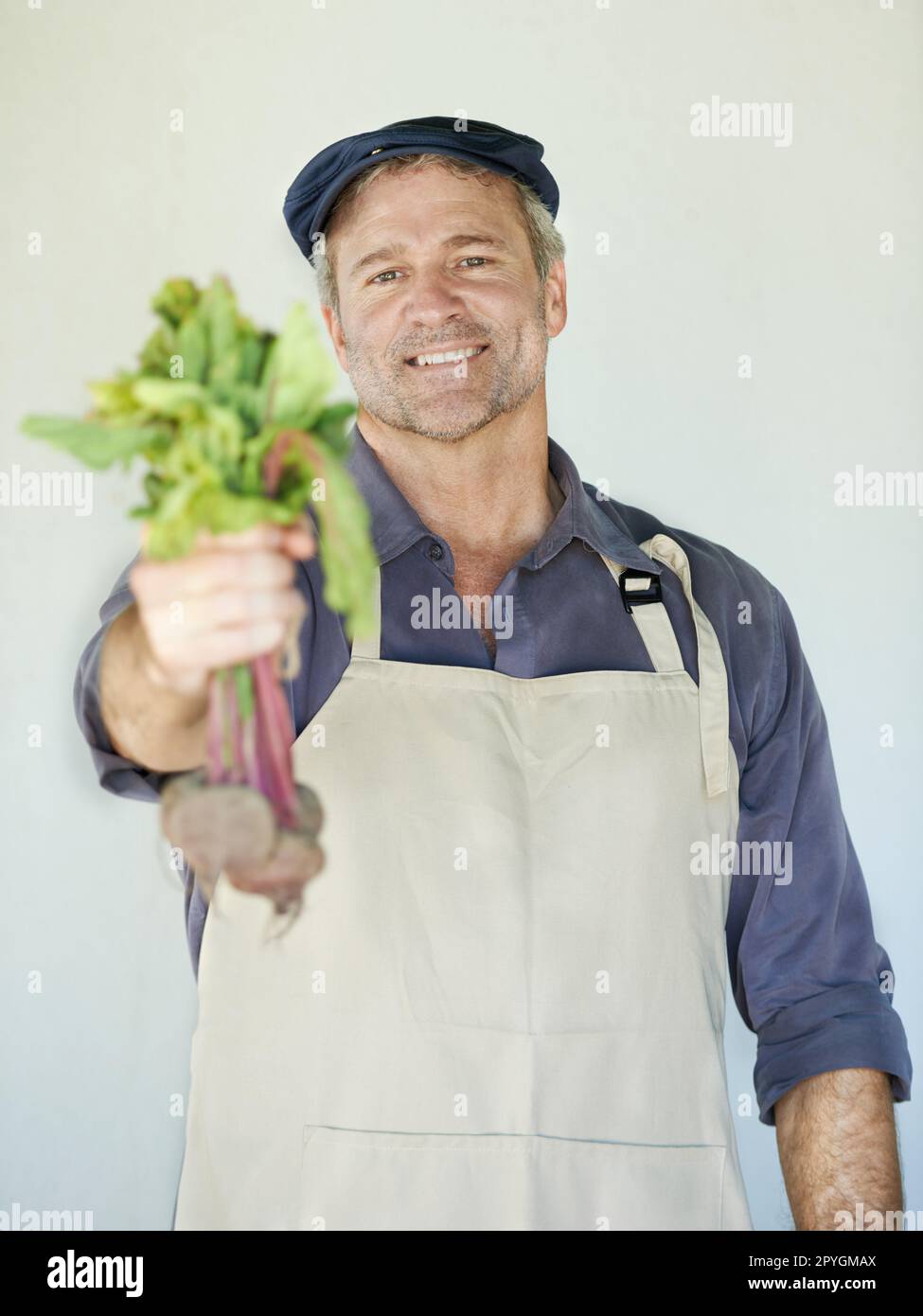 Du solltest unsere probieren. Ein reifer Mann, der einen Haufen Rote Bete in der Hand hat. Stockfoto