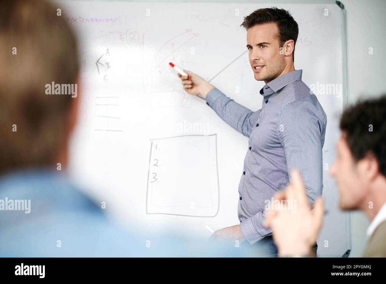 Unser Unternehmen ist auf dem Vormarsch. Ein Mann, der Kollegen in einem Büro ein Whiteboard präsentiert. Stockfoto