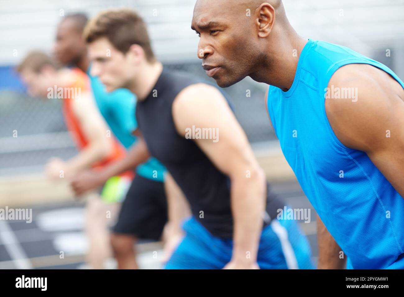 Bereit, fertig... Nahaufnahme eines männlichen Läufers in einer Reihe von anderen Athleten, die im Hintergrund verschwommen sind. Stockfoto