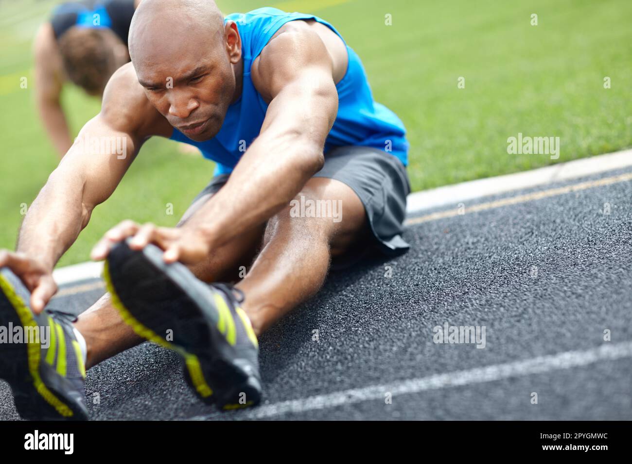Aufwärmphase. Nahaufnahme eines männlichen Athleten, der seine Muskeln auf der Rennstrecke dehnt. Stockfoto