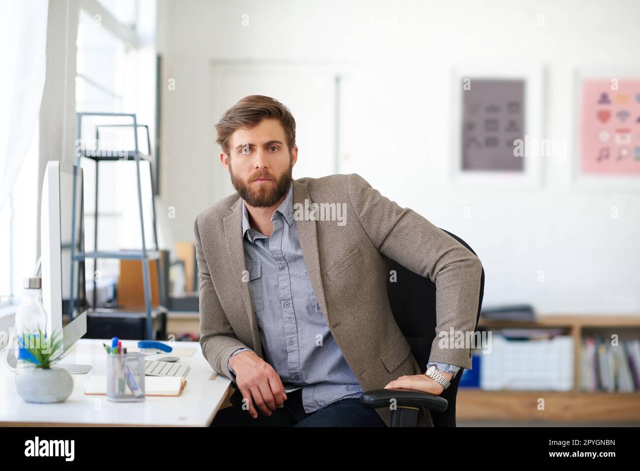 Selbstbewusst und kreativ. Porträt eines gutaussehenden Geschäftsmannes, der in seinem Büro arbeitet. Stockfoto