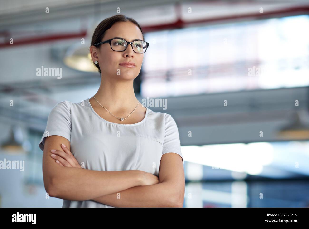 Die Zukunft ist bereit für Veränderungen. Selbstbewusste Geschäftsfrau, die mit einem Industriegebiet im Hintergrund umsichtig wegsieht. Stockfoto