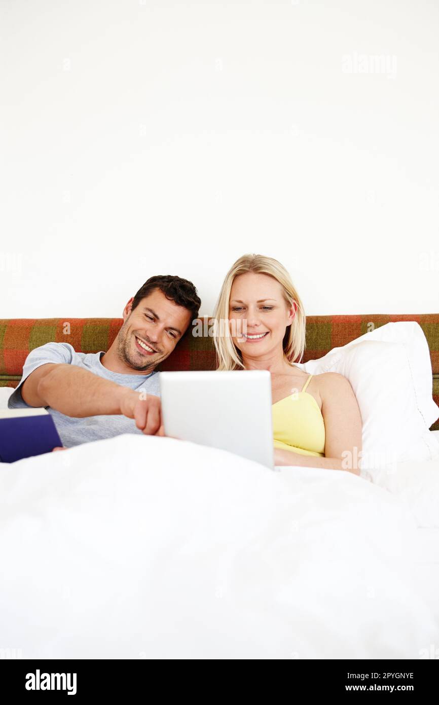 Seht euch das an... Ein junges Paar, das sich im Bett entspannt. Stockfoto