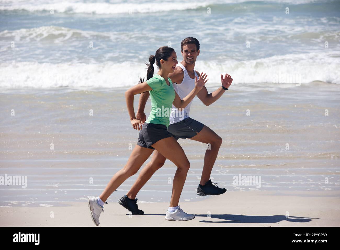 Wer schwitzt, bekommt gute Dinge. Ein junges Paar, das am Strand joggt. Stockfoto