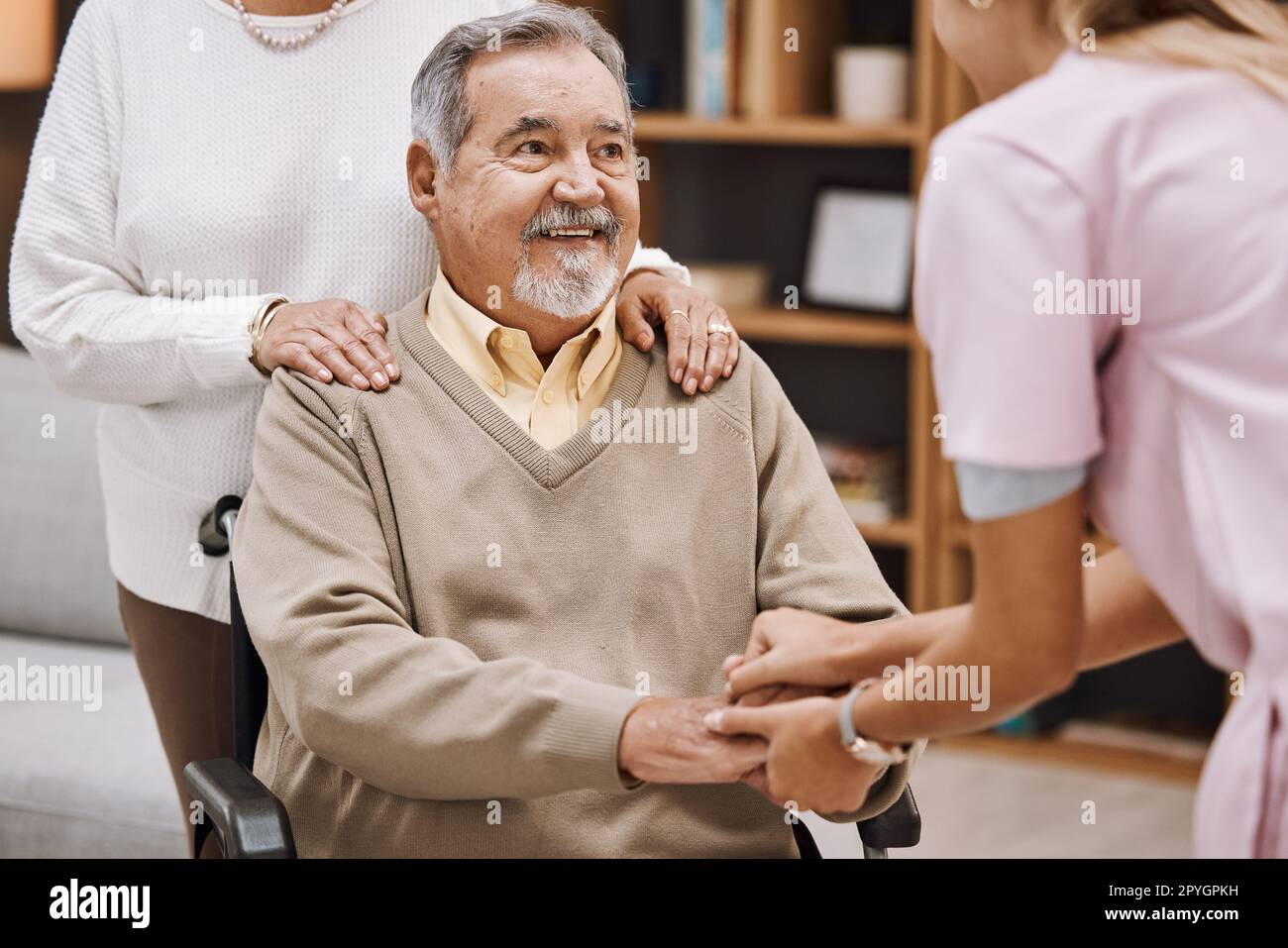 Behindertenpatienten halten sich mit einem Arzt die Hand für Seniorenhilfe, Unterstützung und Vertrauen in Hauskrankenpflege, Physiotherapie und Gesundheitsversorgung. Arzthelferin konsultiert älteren Mann im Rollstuhl bei Pflegeperson willkommen Stockfoto