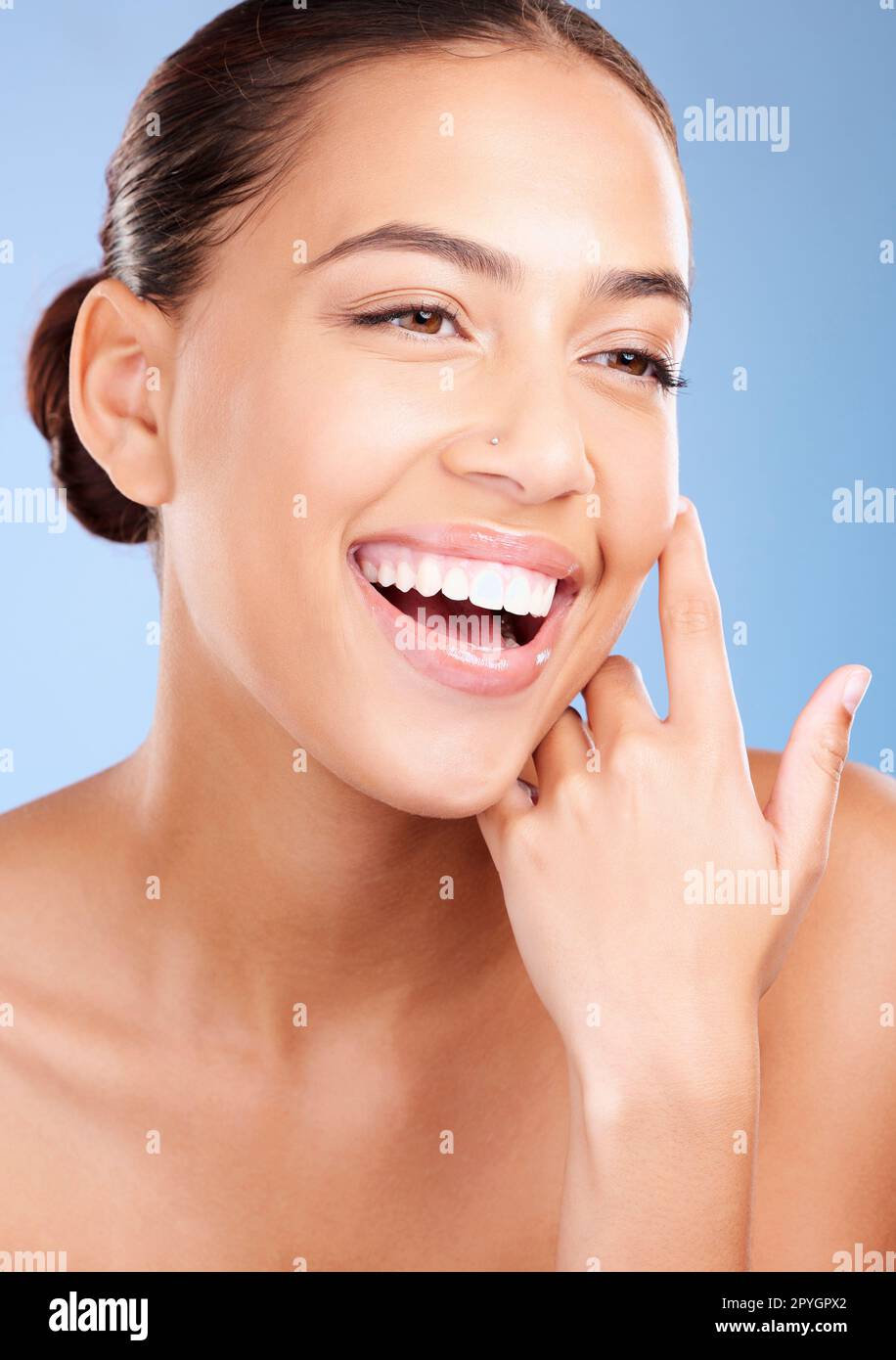 Frau, Hautpflege und Schönheitskosmetik mit Lächeln, natürlichem Leuchten und Glück auf blauem Hintergrund. Model, Kosmetik Studio und glücklich mit strahlender Ästhetik, Haut Gesundheit oder Selbstpflege Wellness im Hintergrund Stockfoto