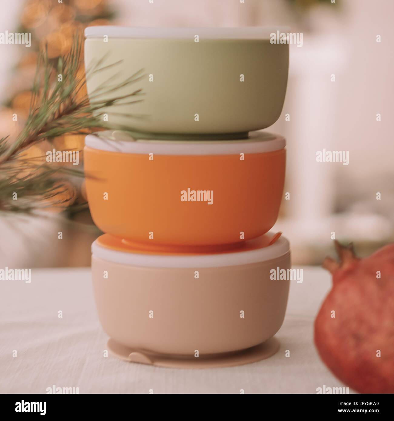 Set mit Babyschalen aus Silikon. Drei Schüsseln mit Deckeln auf dem Hintergrund des Weihnachtsbaums. Quadratischer Rahmen Stockfoto