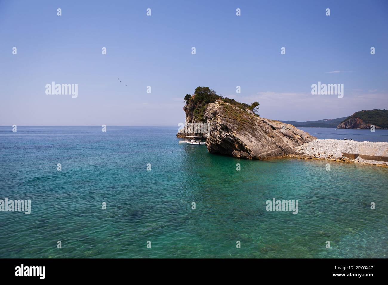 Sehr schöne Aussicht auf das Meer und den Felsen, ein kleines Boot in der Nähe der Klippen, aquamarinklares Wasser. Genießen Sie die Aussicht. Montenegro. Stockfoto