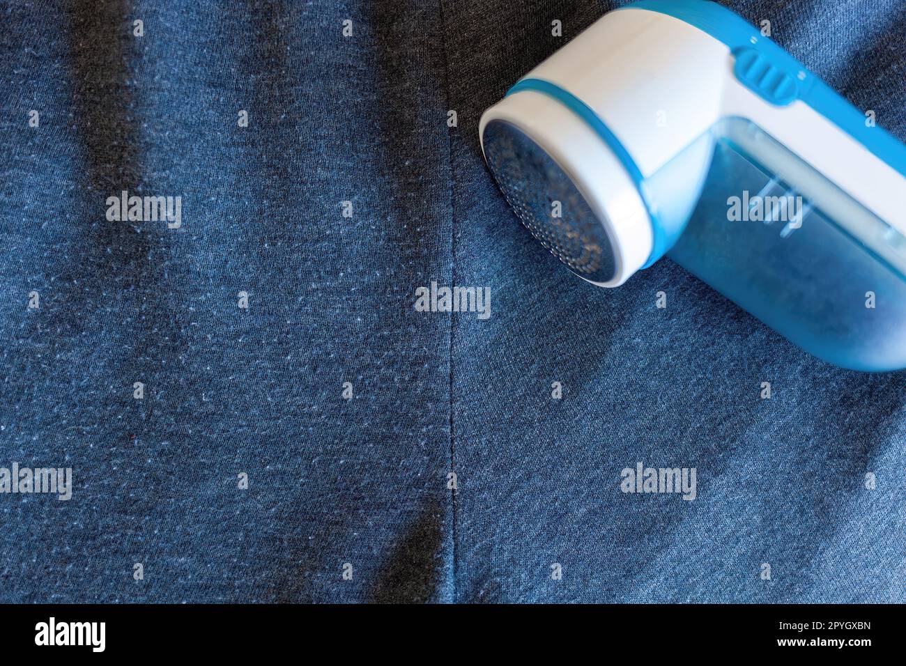 Moderner Rasierer auf grauem Tuch. Dieses Gerät entfernt Fusseln von der Kleidung. Stockfoto