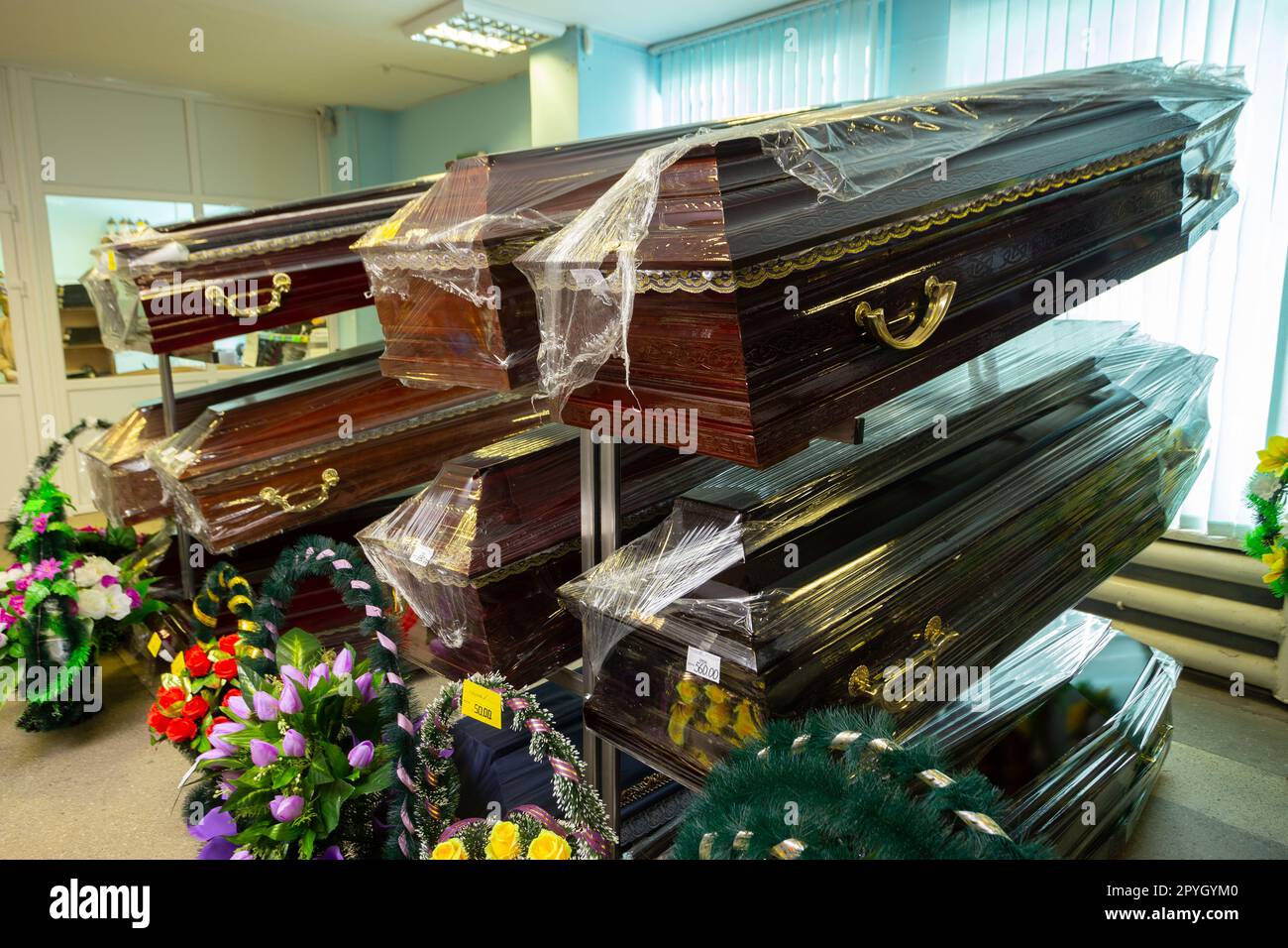 Innenraum des Raumes mit Bestattungszubehör. Geschäft mit Särgen, Beerdigungskränzen und Blumen. Stockfoto