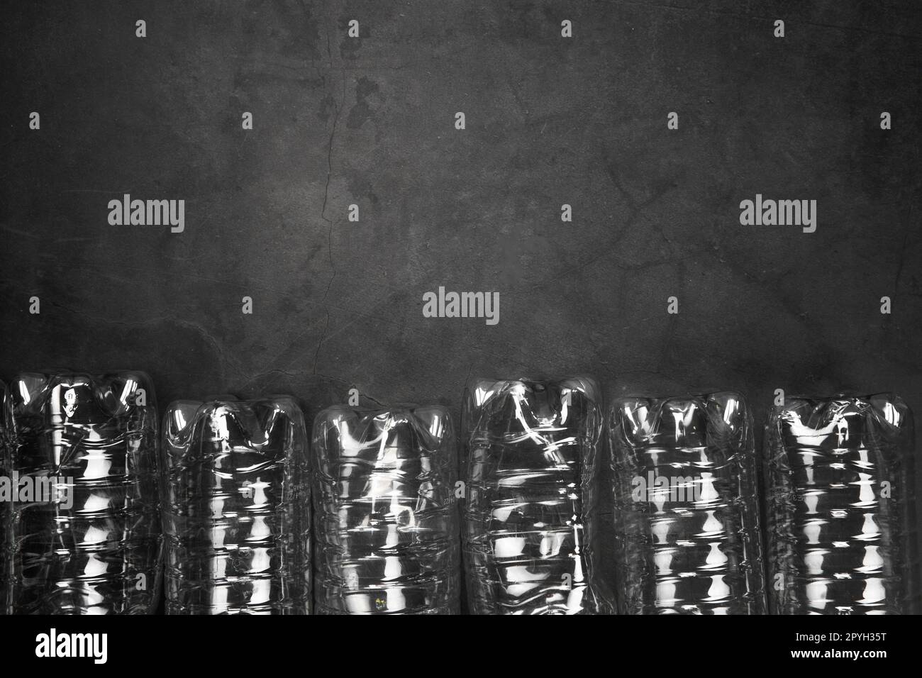 Recycling- und Ökologiekonzept. Sortieren von Haushaltsabfällen, die von oben aufgefangen werden, flach liegend. Leere Kunststoffflaschen mit grauem Betonhintergrund Stockfoto