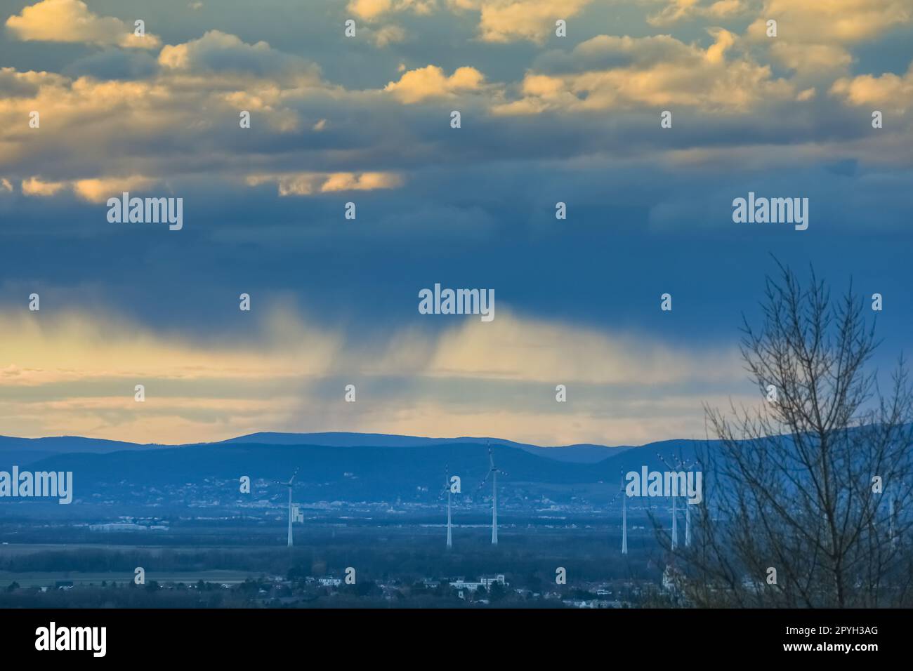 Heftiger Regen unter Wolken bei Sonnenuntergang in einer Landschaft mit Windmühlen Stockfoto