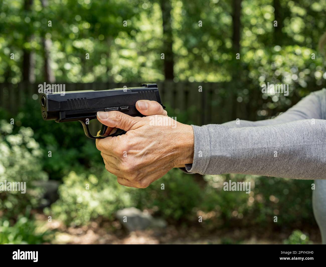 Eine Frau mit einer Sig Sauer 9mm-Pistole, die mit einem Zweihandgriff zielt, übt ihr zweites Amendment direkt in den USA aus. Stockfoto