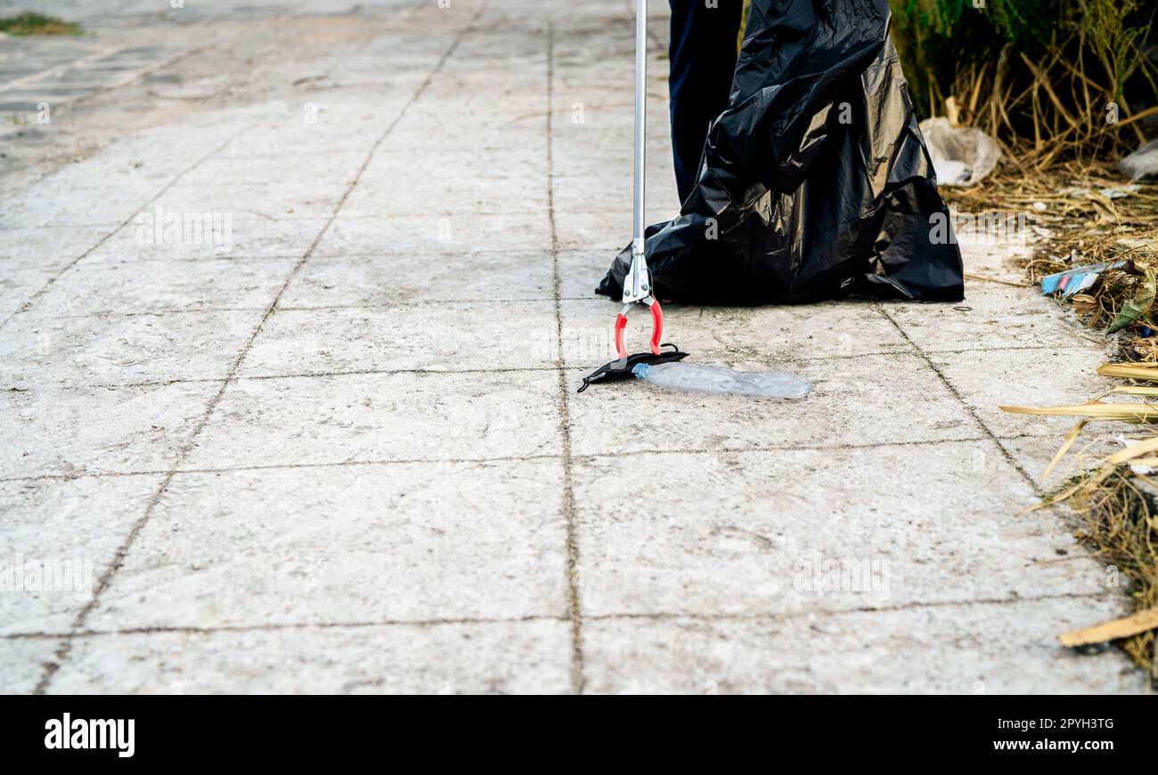 Freiwillige sammeln gebrauchte medizinische Gesichtsmaske in der Nähe Plastikflasche in Müll Plastiktüte für die Reinigung städtische Straße. Den Gemeindemüll aufräumen. Weltumwelttag, rette die Erde. Medizinische Abfälle. Stockfoto