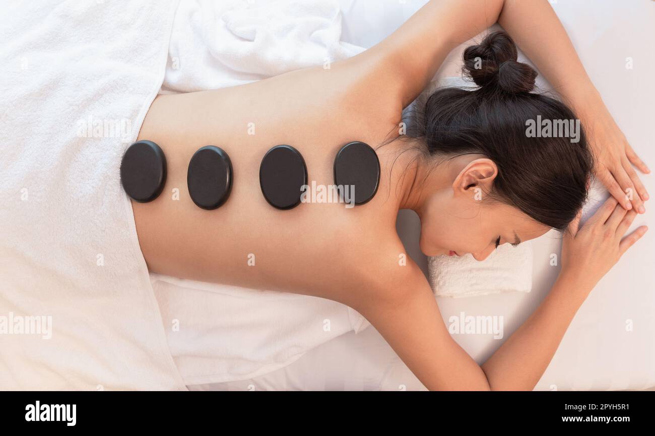 Wunderschöne junge Frau, die sich im Wellnesssalon mit einer Hot-Stone-Massage am Körper entspannen kann. Schönheitsbehandlungen. Stockfoto