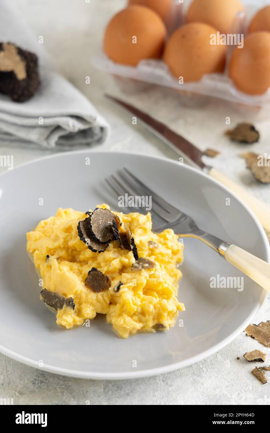 Rühreier mit frischen schwarzen Trüffeln aus Italien, serviert auf einem Teller aus nächster Nähe, Gourmet-Frühstück Stockfoto