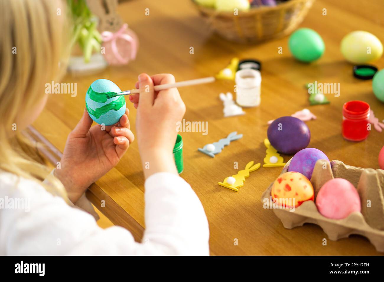 Letle Kinderhände malen Ostereier auf Holztisch. Vorbereitung auf die Osterfeier. Stockfoto