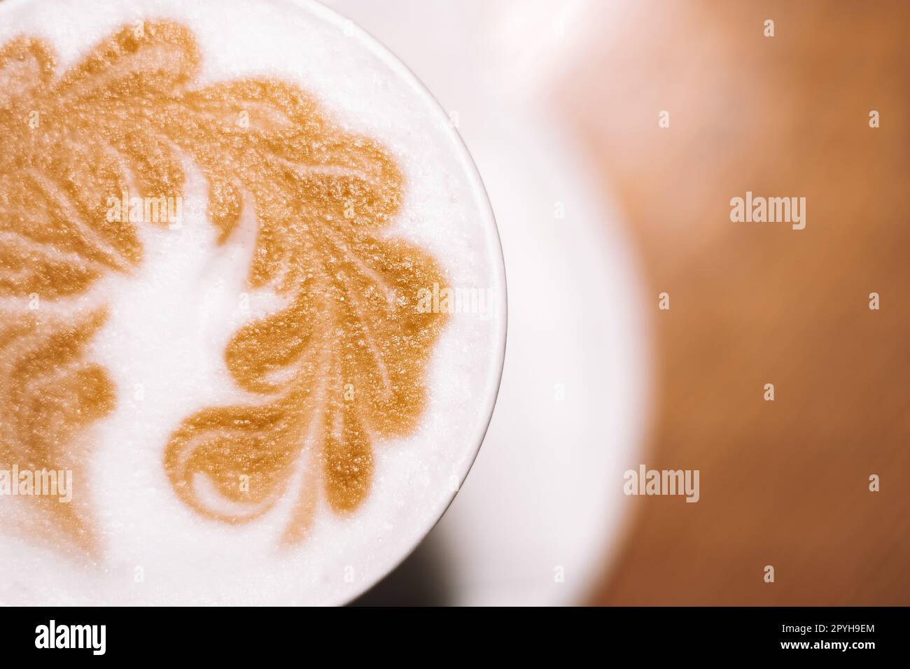 Köstlicher Cappuccino-Kaffee in Tasse Becher Glas Latte mit saurer Sahne Milchschaum mit gemustertem Dorn auf weißer Keramikplatte Stockfoto