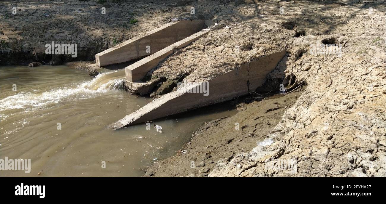 Ein großer Abfluss in der Stadt leitet Abwasser in einen Kanal, der in den Fluss fließt. Umweltproblem. Der Begriff Umweltschutz und Ökologie. Betonstruktur. Stockfoto