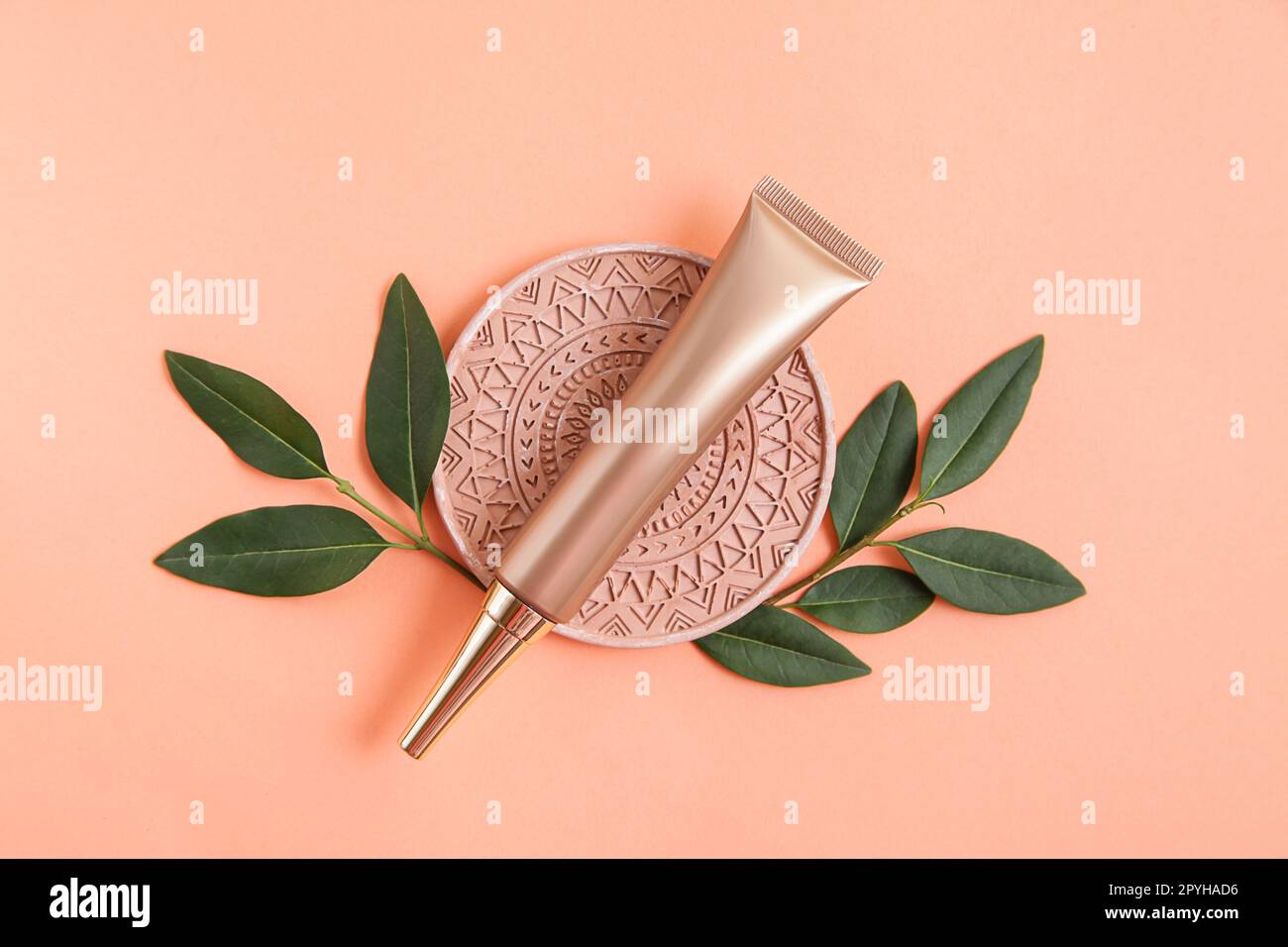 Goldene Kosmetikröhre, heller, pastellfarbener Mandala-Hintergrund. Natürlicher Minimalismus, minimales Styling, Stillleben. Branding-Layout, Hautpflege und Modell Stockfoto