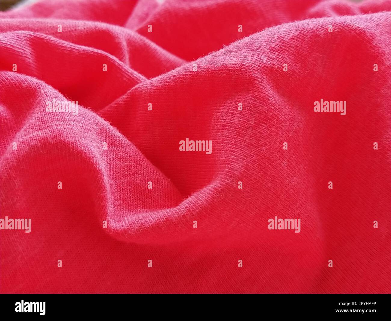 Leuchtendes rosa oder magentafarbenes Polyestergewebe, zerknittert oder achtlos gefaltet. Gesättigter Hintergrund. Unschärfe-Effekt Stockfoto