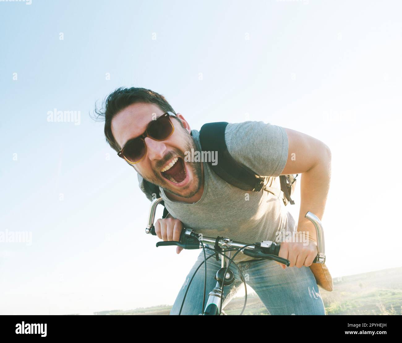 Aktiver Sportler mit aufgeregtem Gesichtsausdruck beim Erkunden und Reisen mit dem Mountainbike auf der Straße. Bild im Vintage-Film-Filterstil. Stockfoto