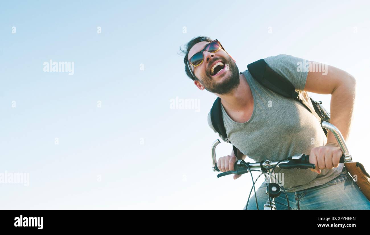 Aktiver Sportler mit aufgeregtem Gesichtsausdruck beim Erkunden und Reisen mit dem Mountainbike auf der Straße. Bild im Vintage-Film-Filterstil. Stockfoto
