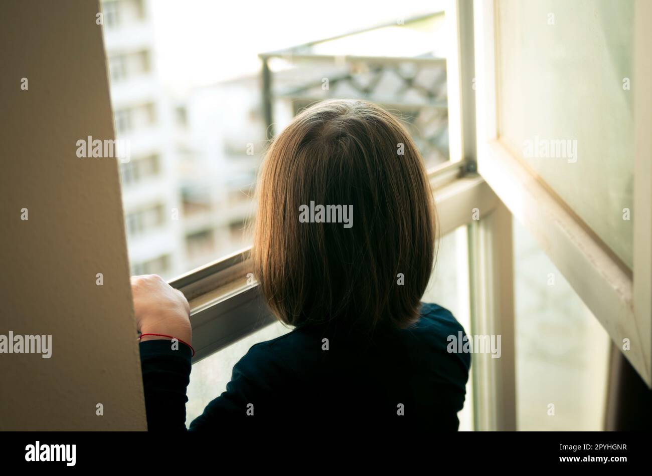 Kleines Mädchen schaut aus dem Fenster Stockfoto
