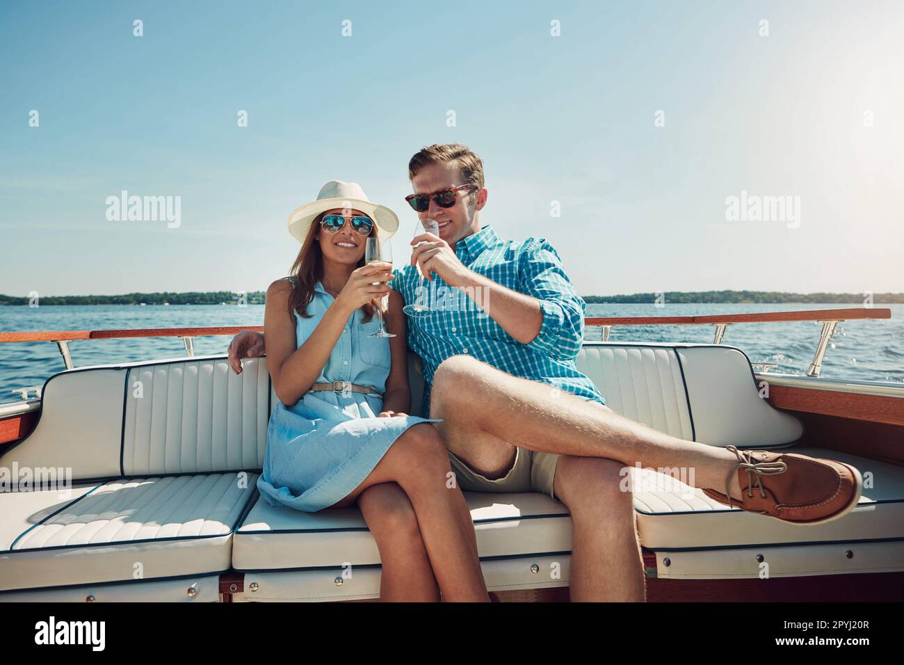 Sekt an Bord. Ein junges Paar, das Champagner auf einer Bootsfahrt trinkt. Stockfoto