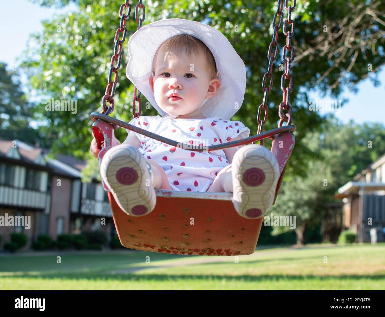 Ein weißes Mädchen, das an einem sonnigen Sommertag in einer Schaukel sitzt Stockfoto