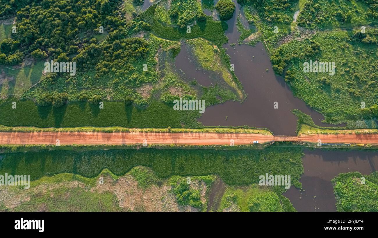 Luftaufnahme der Transpantaneira-Feldstraße, die einen Fluss durch eine Holzbrücke überquert, üppige Vegetation rund um North Pantanal Wetlands, Mato Grosso, Brasilien Stockfoto