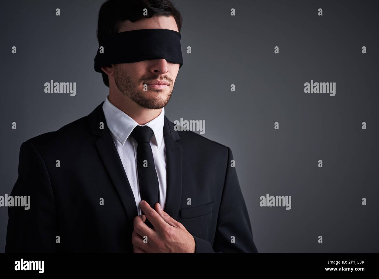 So gut, dass er mit geschlossenen Augen Geschäfte machen kann. Studiofoto eines jungen Geschäftsmannes mit Augenbinde vor grauem Hintergrund. Stockfoto