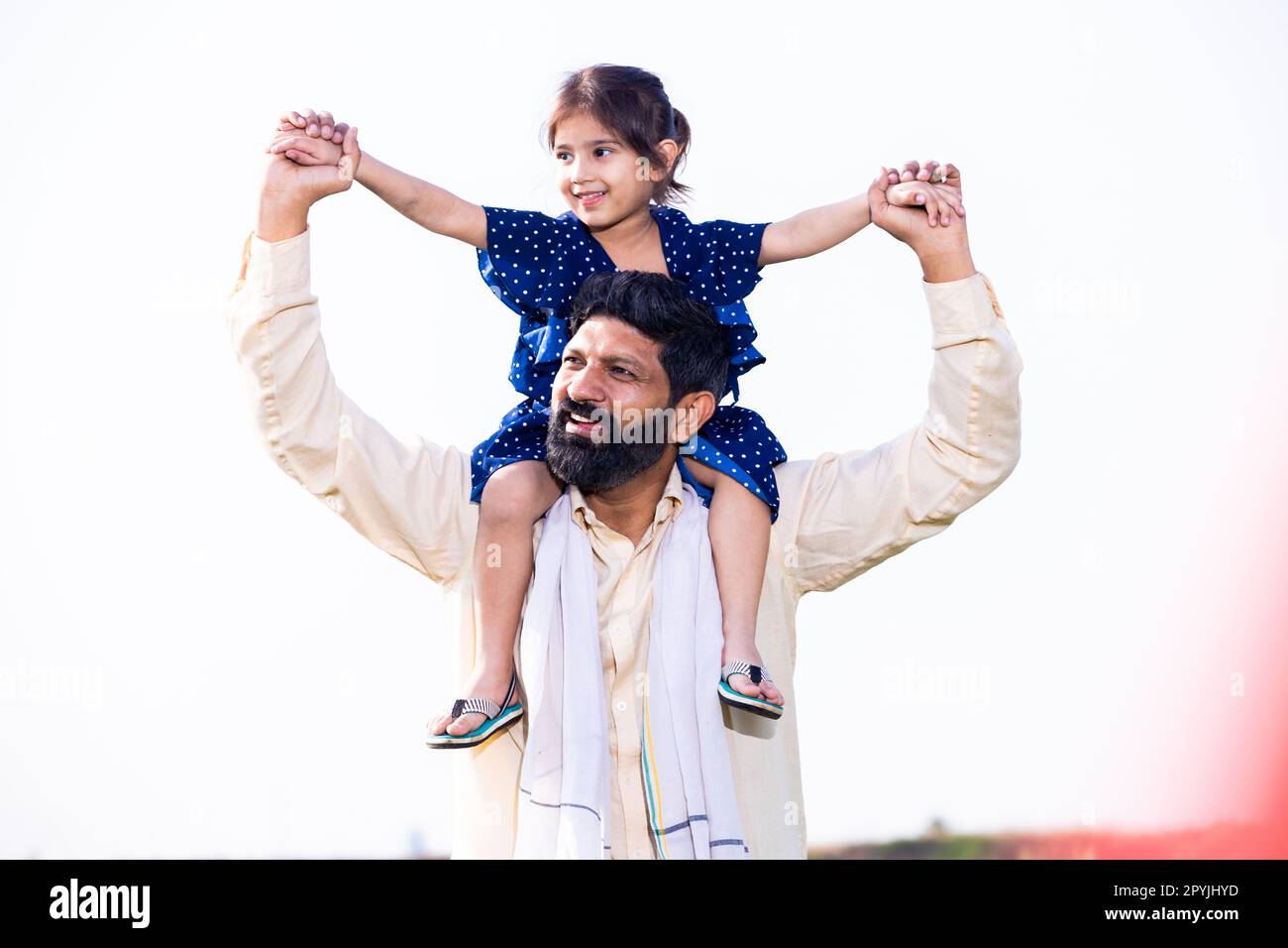 Glückliche indische kleine Tochter, die auf der Vater-Schulter sitzt, Spaß miteinander hat, Mädchen-Kind, Spaß im Freien, Beziehungsaufbau. Niedriger Winkel. Stockfoto