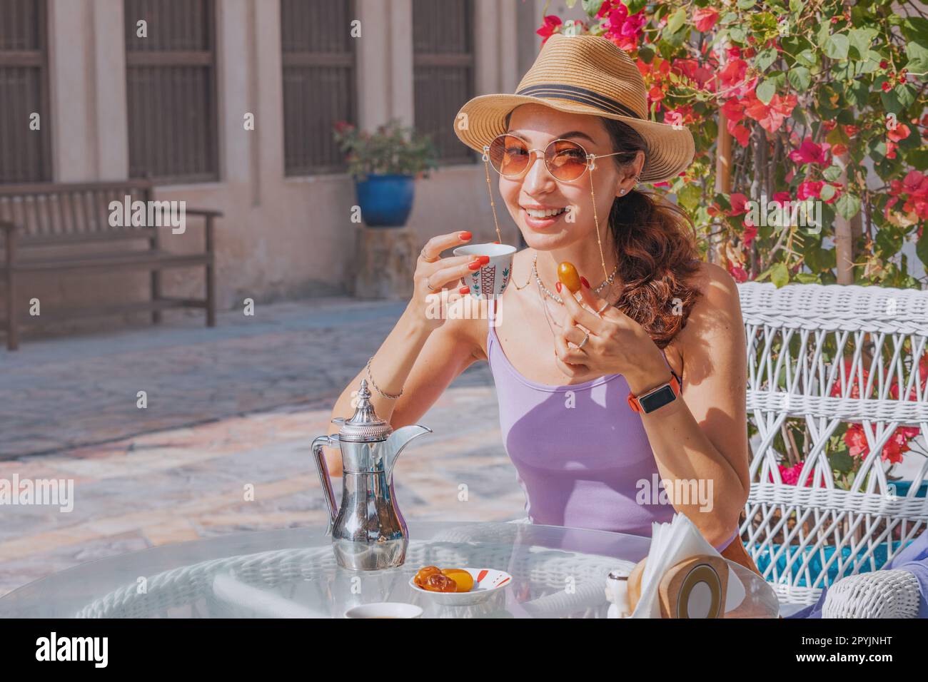 Ein Mädchen in Dubai genießt das einfache Vergnügen einer Tasse arabischen Kaffees, begleitet von der Süße frischer Datteln in einem bezaubernden Café Stockfoto