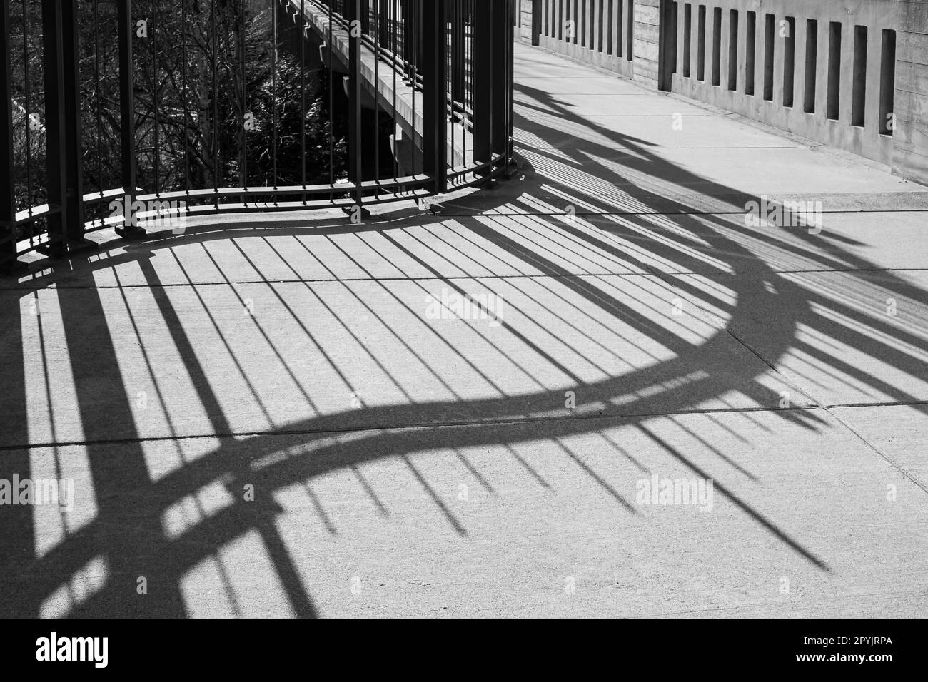 Geländerschatten auf der Brücke. Das Brückengeländer wirft einen Schatten. Abstrakter Brückenschatten. Stadtbild, Straßenfoto, niemand Stockfoto
