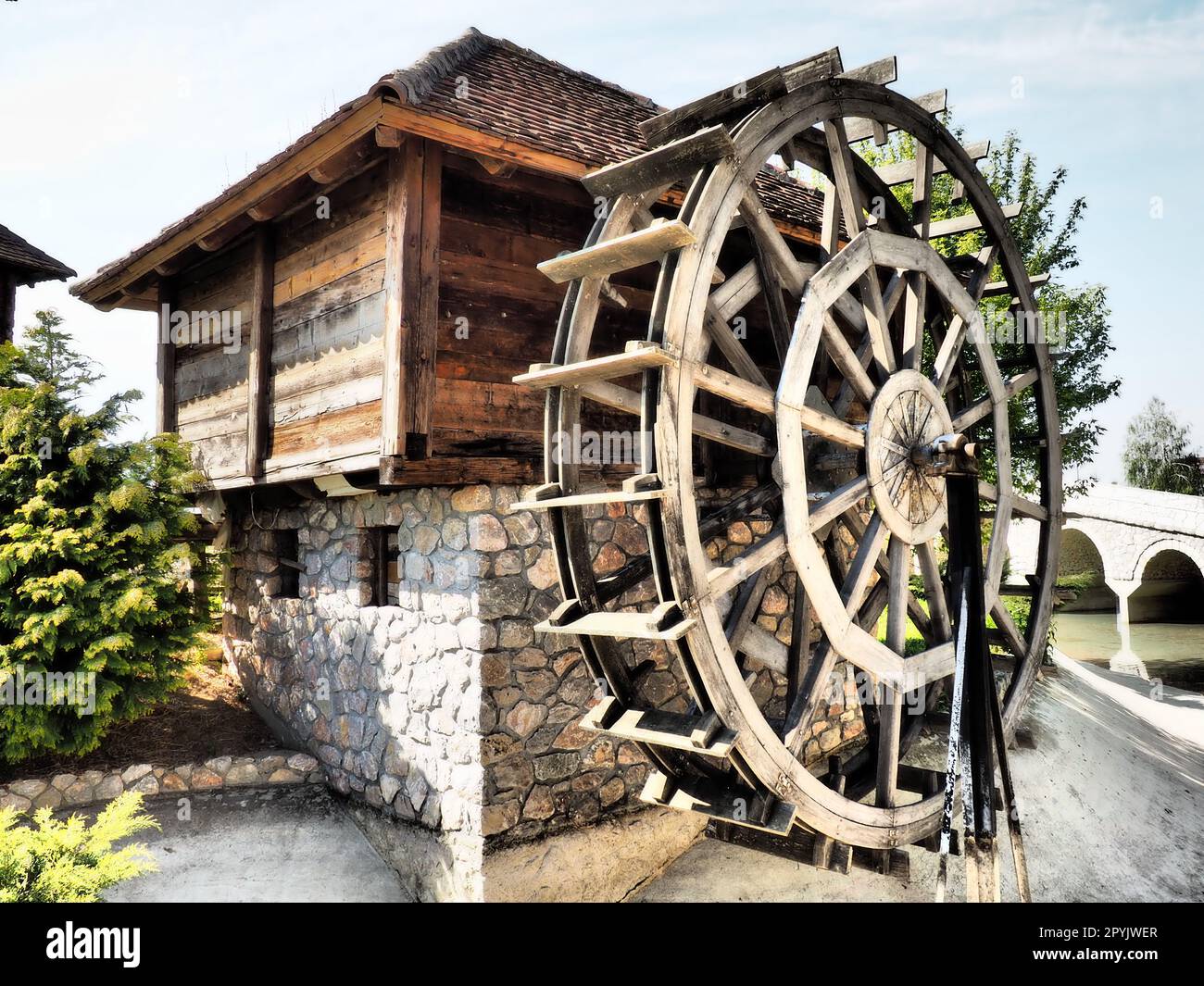 Wassermühle aus Holz Eine hydraulische Struktur, die Wasserkraft aus einem Wasserrad nutzt. Sinnvolle Arbeit mit einem Zahnradsatz Stockfoto