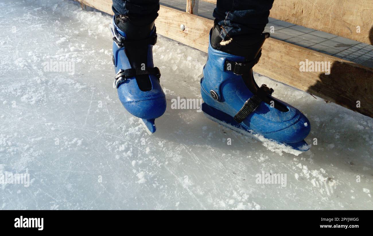 Füße mit Rollschuhen. Sportuniformen und -Ausrüstung. Eislaufbahn. Lange Schatten auf Eis von der niedrigen Wintersonne. Stockfoto