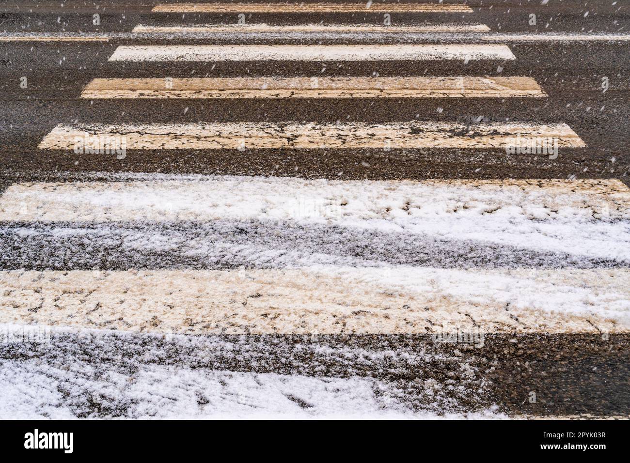 Schnee, Eis und Winterschlamm an einer Fußgängerüberquerung Stockfoto