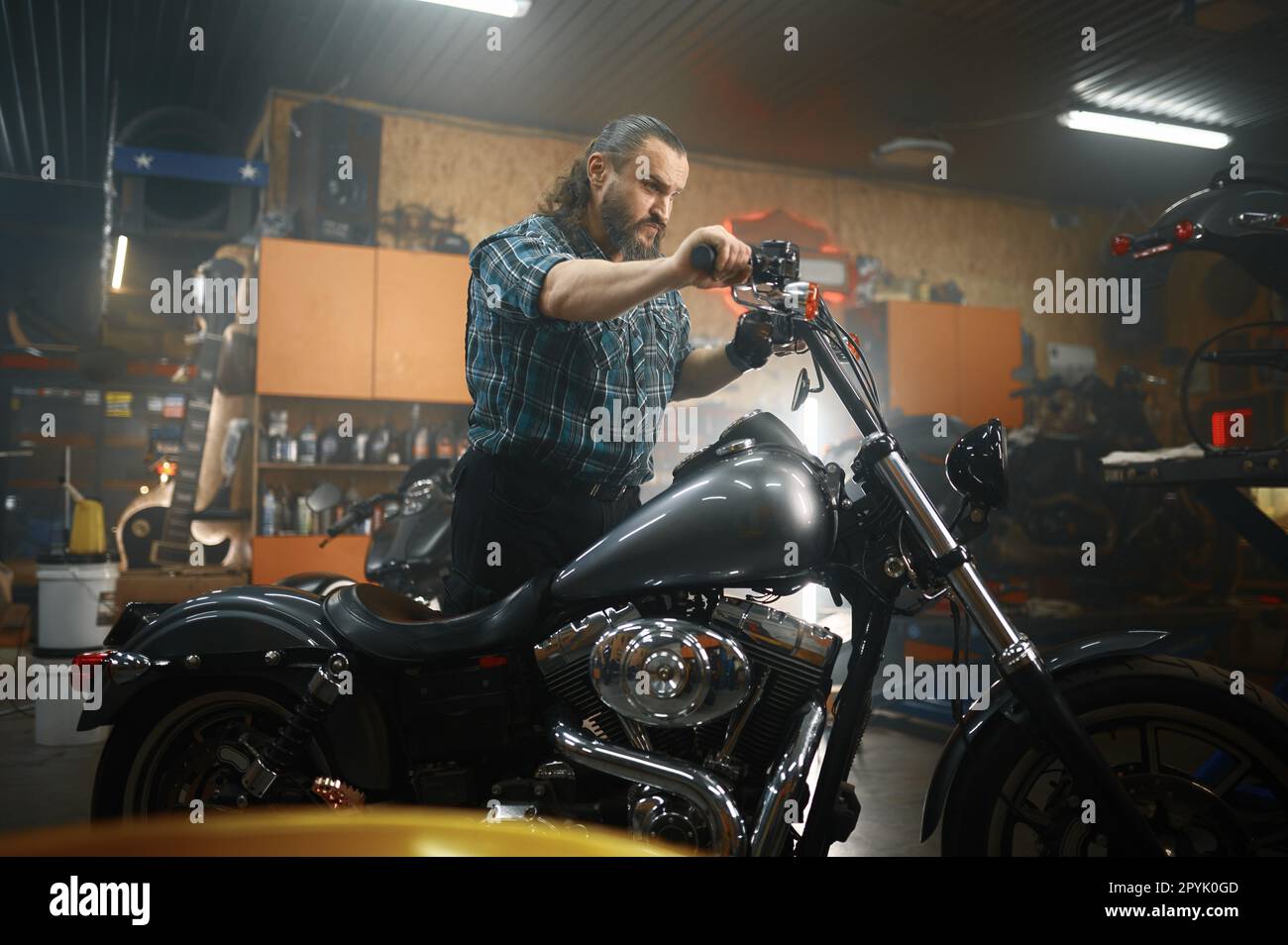 Reifer männlicher Biker auf seinem neuen Motorrad in der Garage Stockfoto