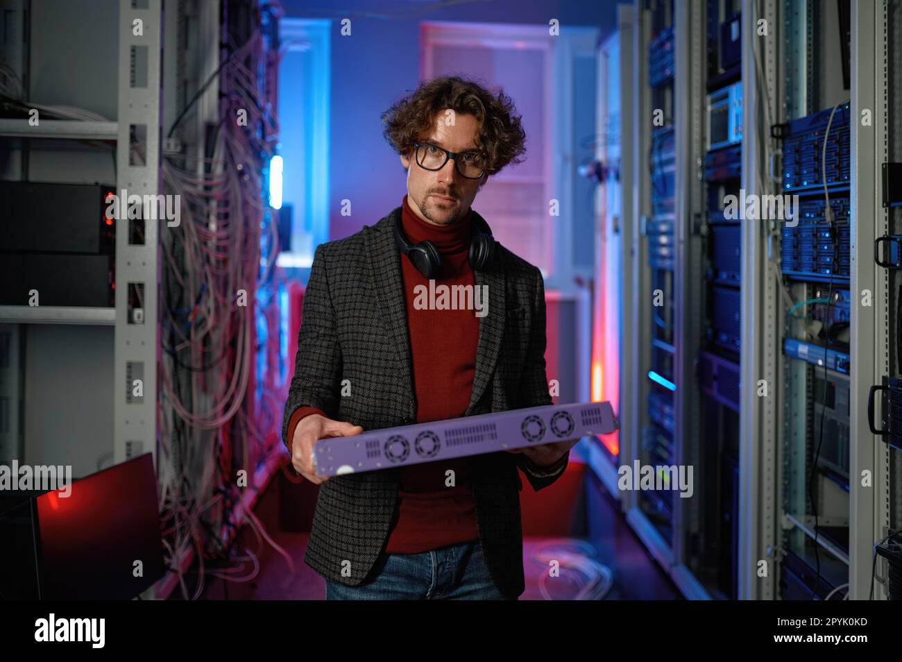 Porträt eines IT-Spezialisten, der im Serverraum Hardware in der Hand hält Stockfoto