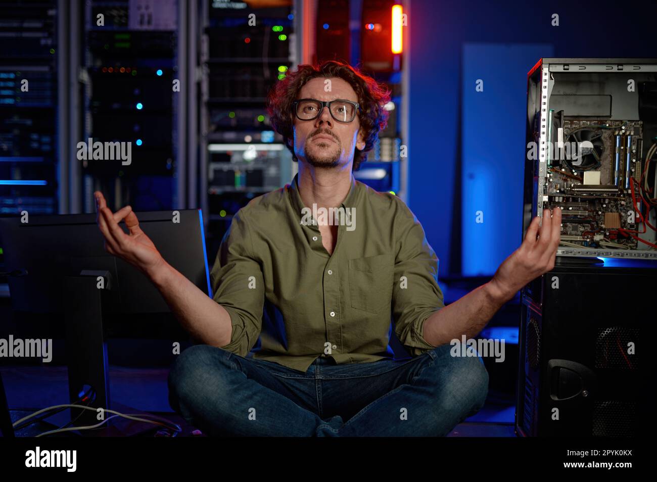 Leidenschaftlicher Techniker meditiert im Serverraum eines modernen Rechenzentrums Stockfoto